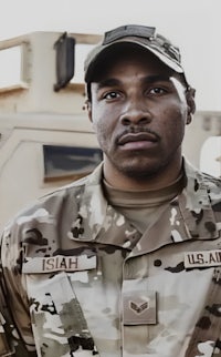 a man in a camouflage uniform is standing in front of a military vehicle