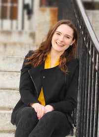 a smiling young woman sitting on steps